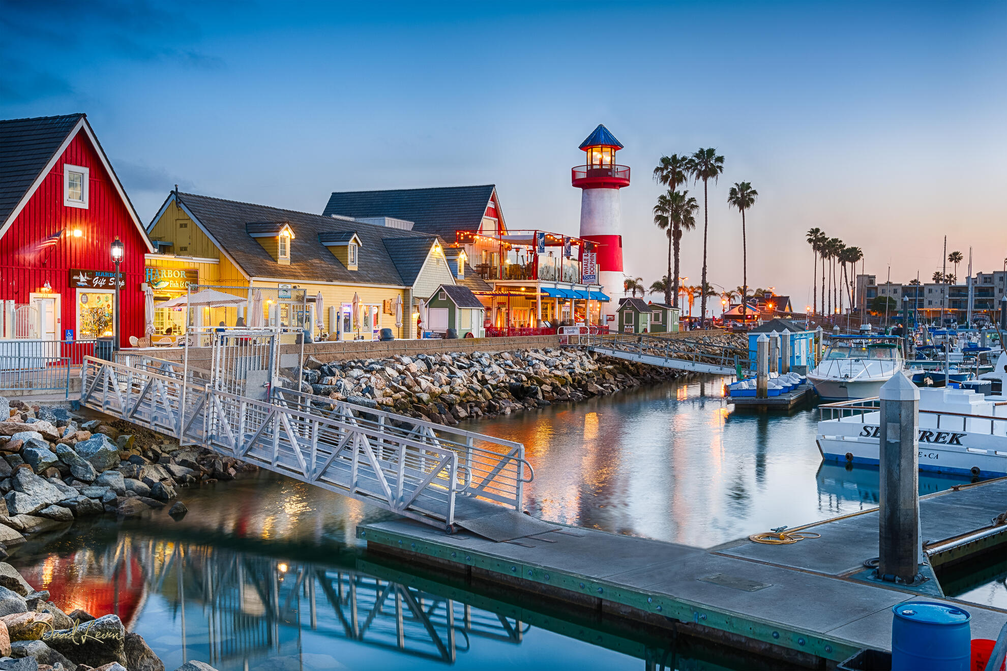 Oceanside Harbor Village at Dusk Oceanside Harbor Village at dusk with glowing harbor lights, colorful waterfront buildings, boats, and reflections in Oceanside, California.